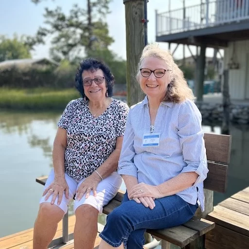 A Village Neighbors Volunteer sitting with a member on a pier over the water.